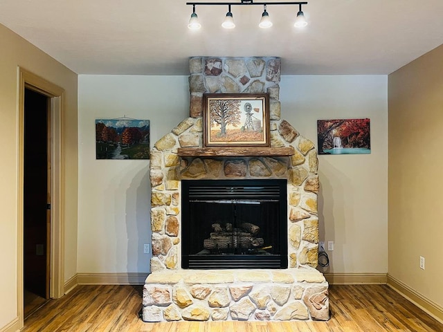 interior details featuring a fireplace, wood finished floors, and baseboards