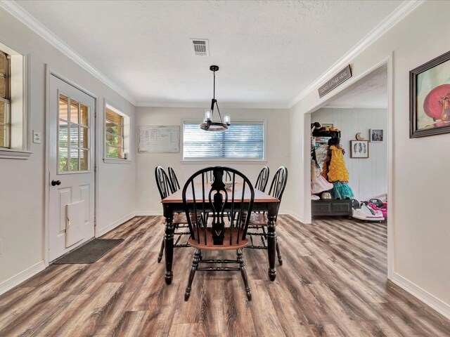 dining area featuring hardwood / wood-style floors, a textured ceiling, and ornamental molding