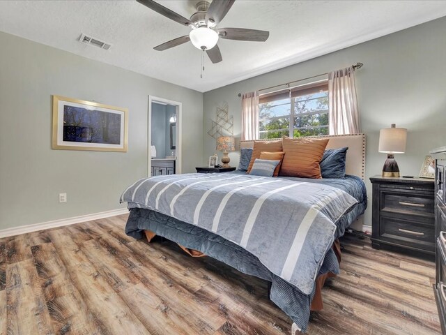 bedroom featuring wood-type flooring, a textured ceiling, ensuite bathroom, and ceiling fan