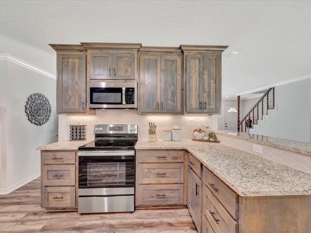 kitchen with light hardwood / wood-style flooring, backsplash, kitchen peninsula, crown molding, and appliances with stainless steel finishes