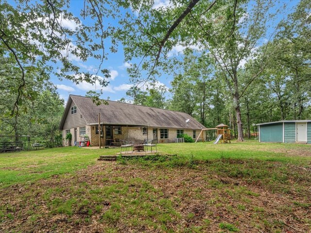 rear view of property featuring a patio, a playground, and a lawn