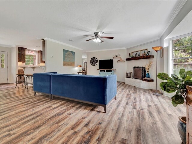 living room with light wood-type flooring, ceiling fan, and ornamental molding