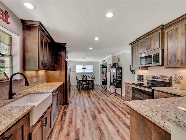 kitchen with light stone countertops, appliances with stainless steel finishes, light hardwood / wood-style flooring, and plenty of natural light