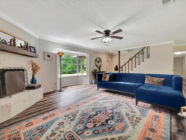 living room featuring ornamental molding, a textured ceiling, ceiling fan, a fireplace, and dark hardwood / wood-style floors