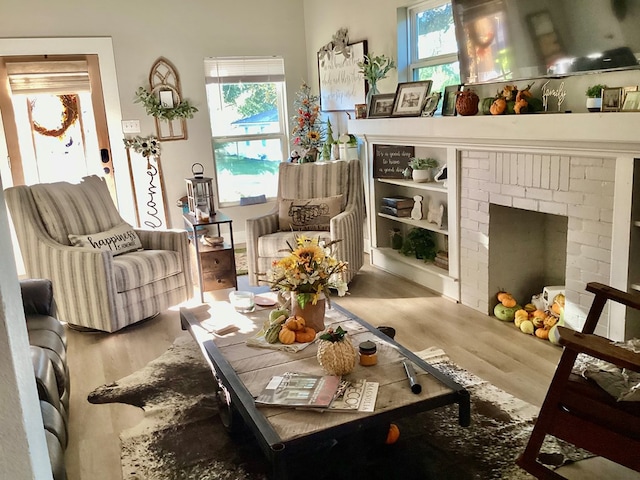 sitting room with plenty of natural light, wood-type flooring, and a brick fireplace