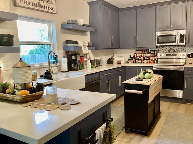 kitchen with tasteful backsplash, stainless steel appliances, sink, light hardwood / wood-style flooring, and a kitchen island