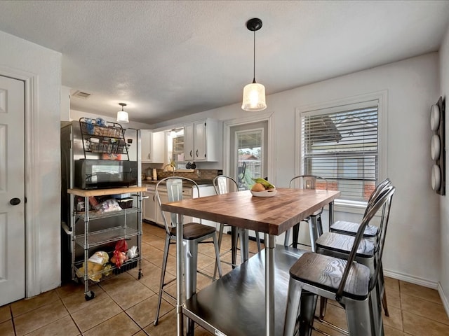 dining area with plenty of natural light, light tile patterned floors, and a textured ceiling