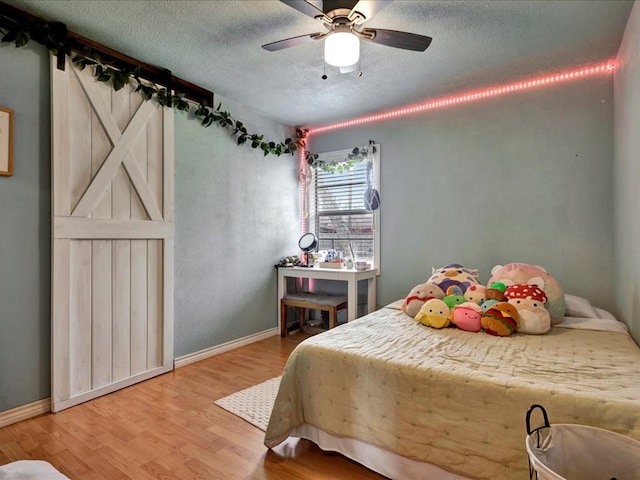 bedroom with hardwood / wood-style floors, ceiling fan, and a textured ceiling