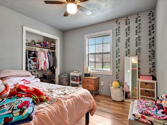 bedroom with a closet, light hardwood / wood-style flooring, and ceiling fan