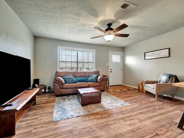 living room featuring ceiling fan, light hardwood / wood-style floors, and a textured ceiling