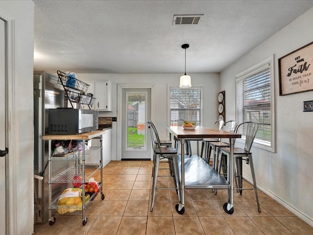 dining space featuring light tile patterned flooring and a textured ceiling