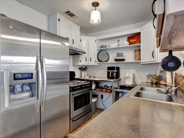 kitchen featuring a textured ceiling, stainless steel appliances, sink, pendant lighting, and white cabinets