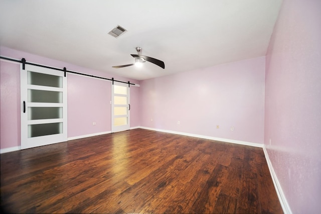 206 Spyglass Dr, Lufkin, TX 75901 - spare room featuring a barn door, a ceiling fan, and dark wood-style flooring
