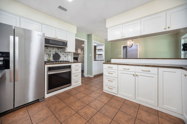 206 Spyglass Dr, Lufkin, TX 75901 - kitchen with appliances with stainless steel finishes, white cabinetry, tasteful backsplash, dark tile patterned floors, and a peninsula