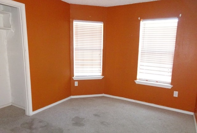 carpeted empty room featuring baseboards