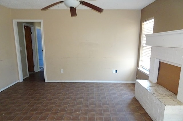 unfurnished living room featuring a fireplace, baseboards, and a ceiling fan