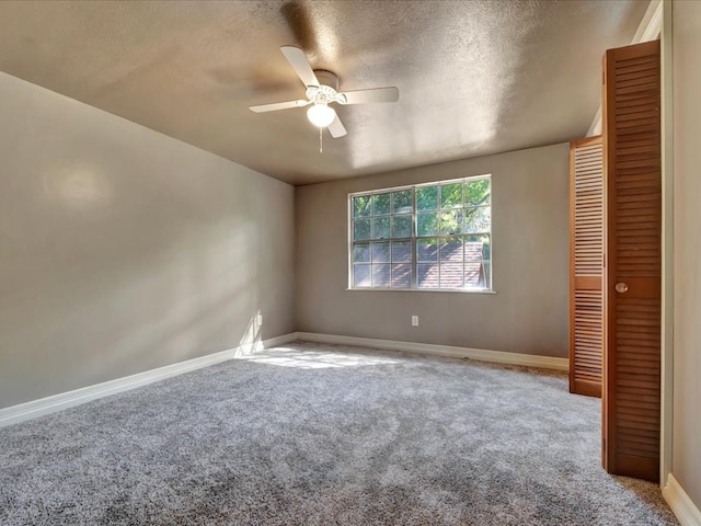 carpeted empty room featuring a textured ceiling and ceiling fan