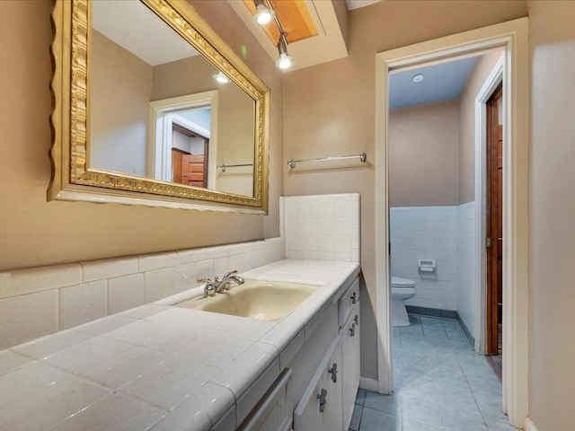 bathroom featuring tile patterned flooring, vanity, toilet, and tile walls