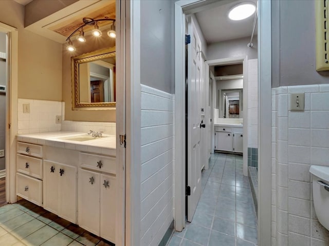 bathroom featuring tile patterned flooring, vanity, and tile walls