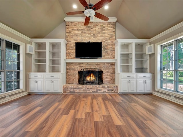 unfurnished living room featuring ceiling fan, a brick fireplace, vaulted ceiling, hardwood / wood-style flooring, and ornamental molding