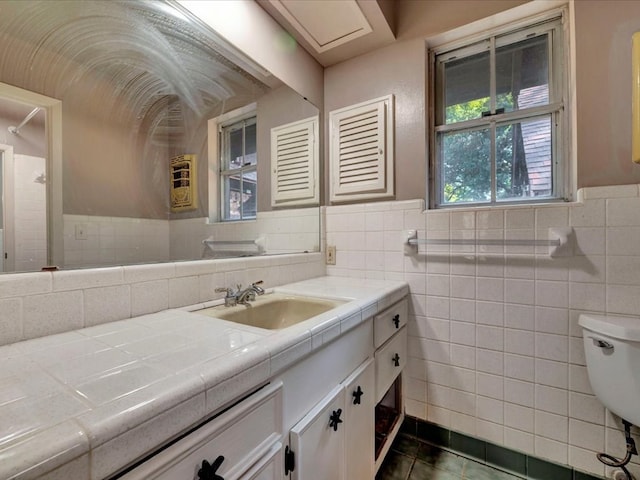 bathroom with tile patterned floors, vanity, tile walls, and toilet