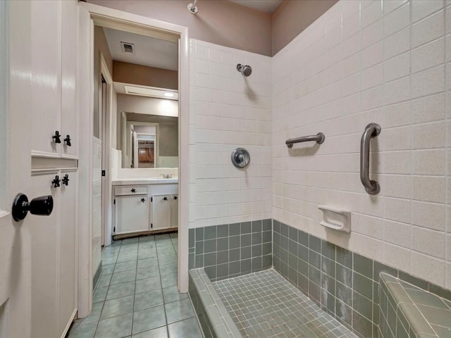 bathroom featuring tile patterned flooring, vanity, and tiled shower