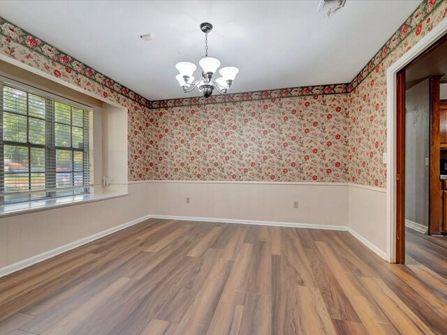 empty room featuring a chandelier and hardwood / wood-style floors