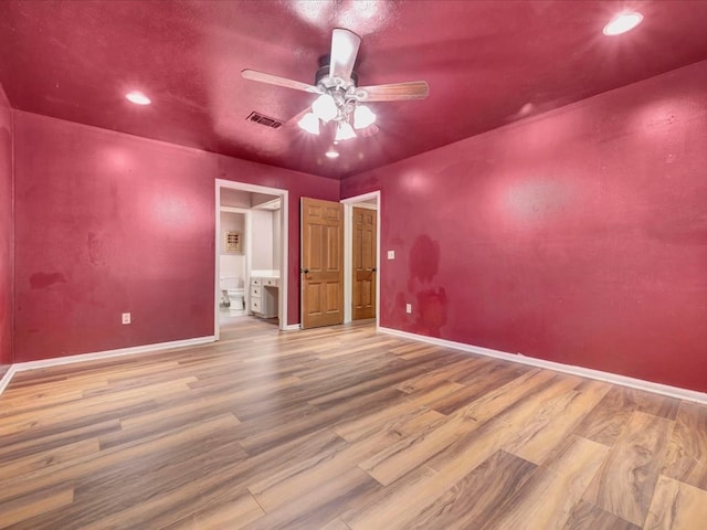 unfurnished bedroom with connected bathroom, ceiling fan, and hardwood / wood-style floors