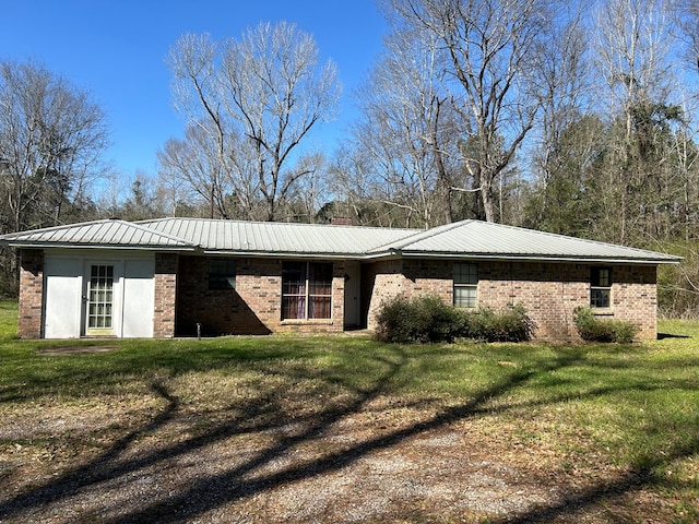 exterior space featuring a yard, brick siding, and metal roof