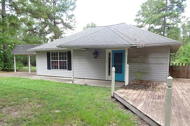 back of property with a yard, a deck, and a carport