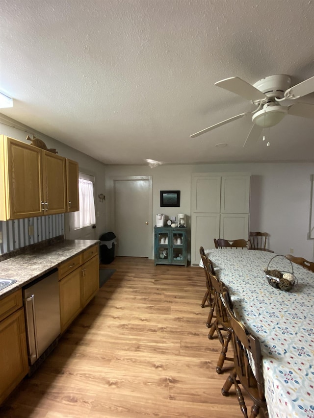 kitchen with stainless steel dishwasher, light wood-type flooring, and a textured ceiling