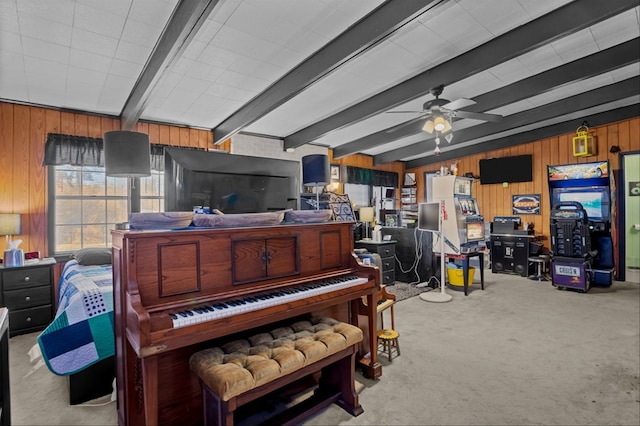 misc room featuring ceiling fan, light colored carpet, beamed ceiling, and wood walls