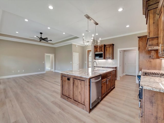 kitchen with light stone countertops, sink, light hardwood / wood-style floors, a kitchen island with sink, and appliances with stainless steel finishes