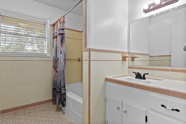 full bath with tile walls, shower / bathtub combination with curtain, vanity, and a wainscoted wall