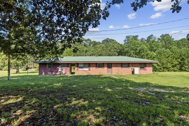 view of front of house with a front yard, metal roof, and central AC unit