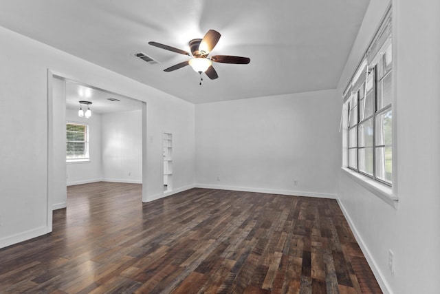 empty room featuring visible vents, baseboards, a ceiling fan, and dark wood-style floors