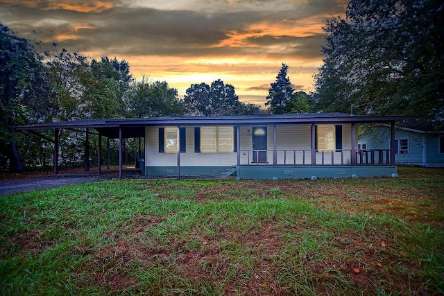 view of front of home featuring a carport, covered porch, and a yard