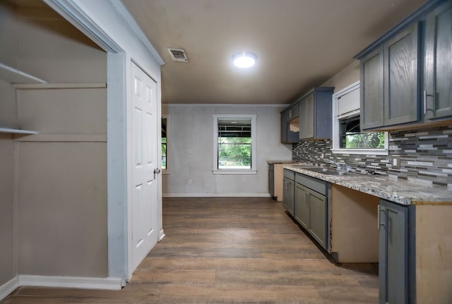 kitchen with light stone countertops, tasteful backsplash, dark wood-type flooring, sink, and gray cabinets