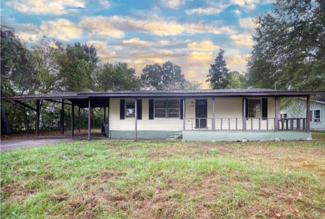 view of front of property with a carport, covered porch, and a lawn