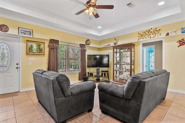 living room featuring a raised ceiling, crown molding, light tile patterned flooring, and ceiling fan