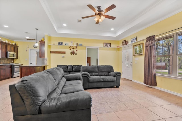 living room featuring light tile patterned floors, a tray ceiling, ceiling fan, and crown molding