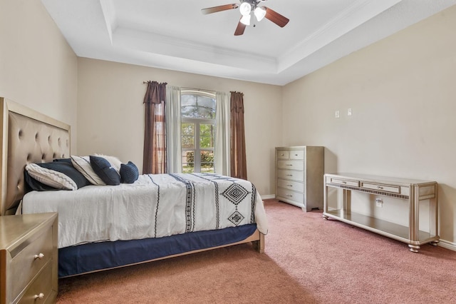 carpeted bedroom with a tray ceiling, ceiling fan, and ornamental molding