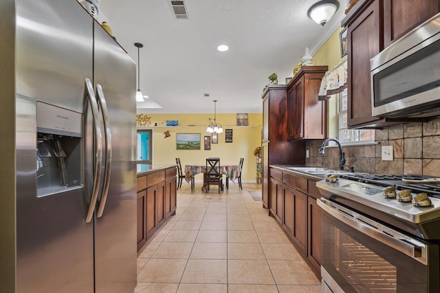 kitchen with sink, hanging light fixtures, decorative backsplash, light tile patterned floors, and appliances with stainless steel finishes