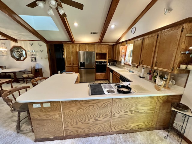 kitchen with kitchen peninsula, appliances with stainless steel finishes, sink, lofted ceiling with beams, and a breakfast bar area