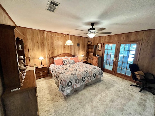 bedroom featuring wood walls, light carpet, access to outside, ceiling fan, and a textured ceiling