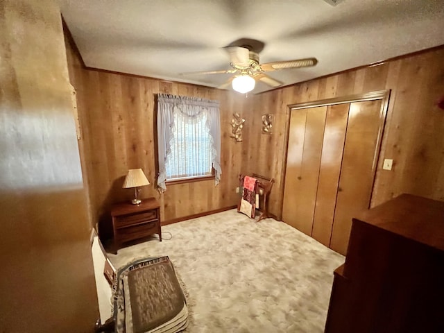 living area featuring ceiling fan and wood walls