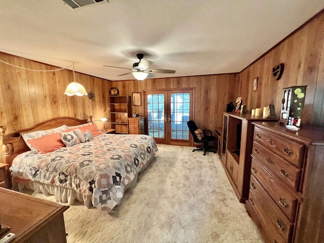 carpeted bedroom featuring french doors, wooden walls, ceiling fan, access to exterior, and a textured ceiling