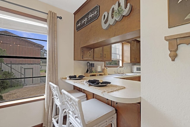 kitchen featuring a breakfast bar, a healthy amount of sunlight, kitchen peninsula, and sink