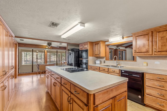 kitchen with black appliances, a center island, light hardwood / wood-style floors, and a textured ceiling