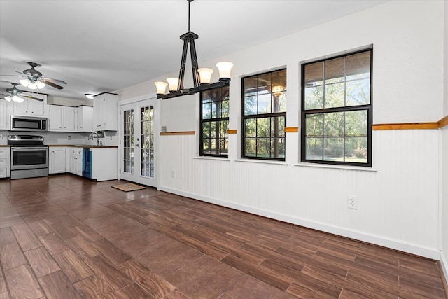 kitchen with appliances with stainless steel finishes, ceiling fan with notable chandelier, sink, decorative light fixtures, and white cabinets